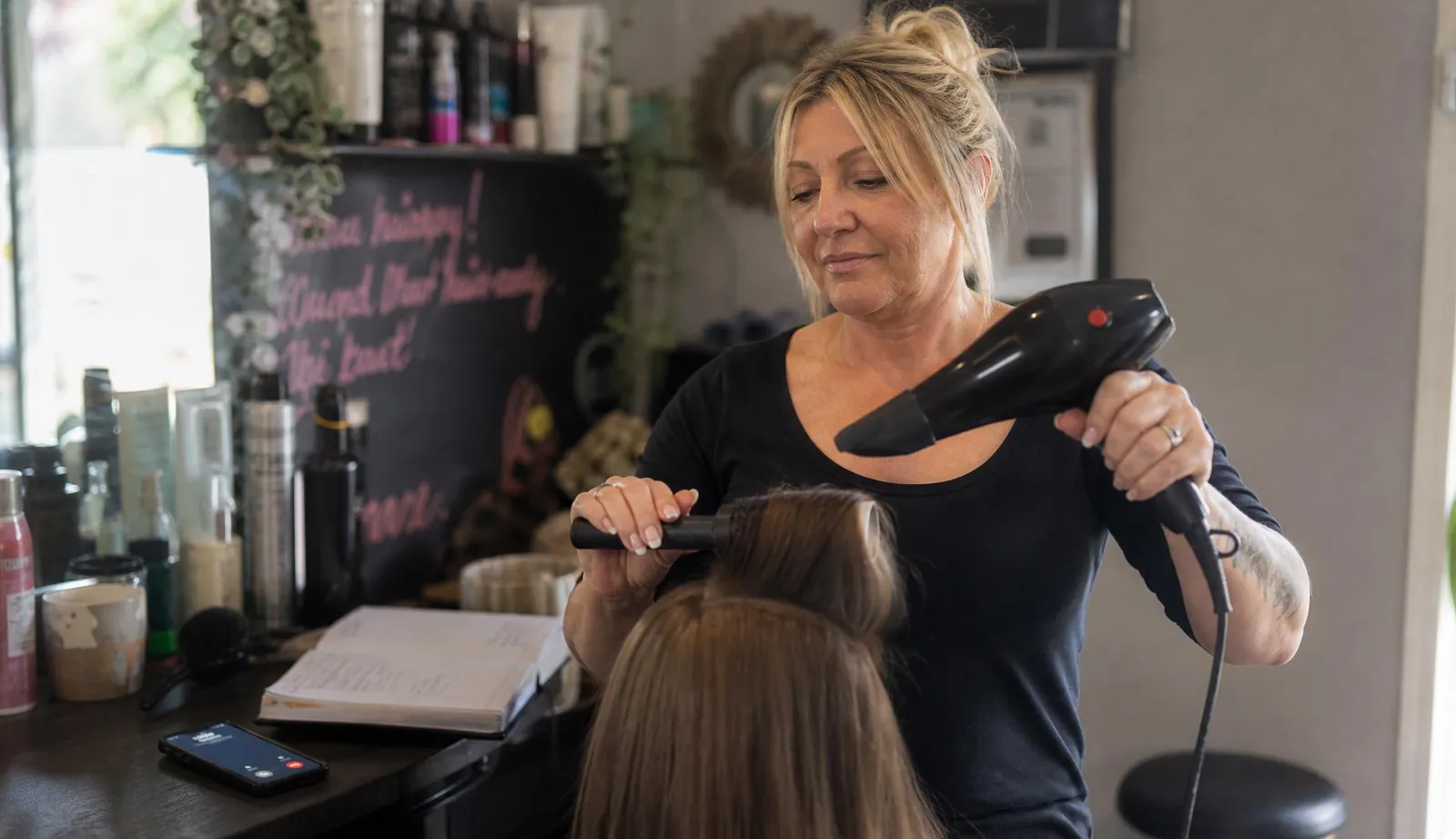 Hairdresser working with a client while a call comes in beside her